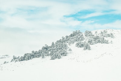 白天多云的天空下，山被雪覆盖